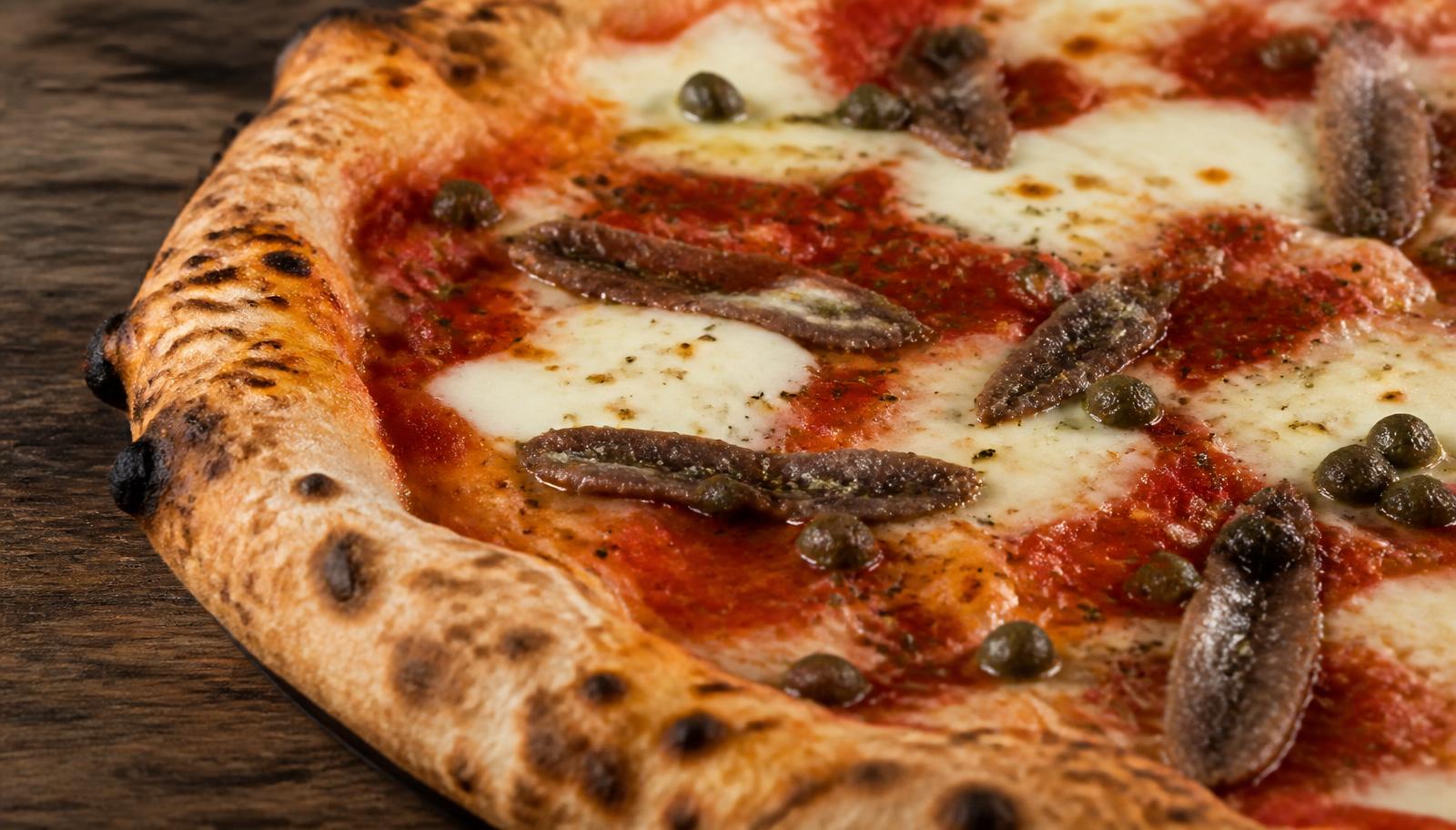 Dettaglio ravvicinato di una pizza napoli con acciughe e capperi