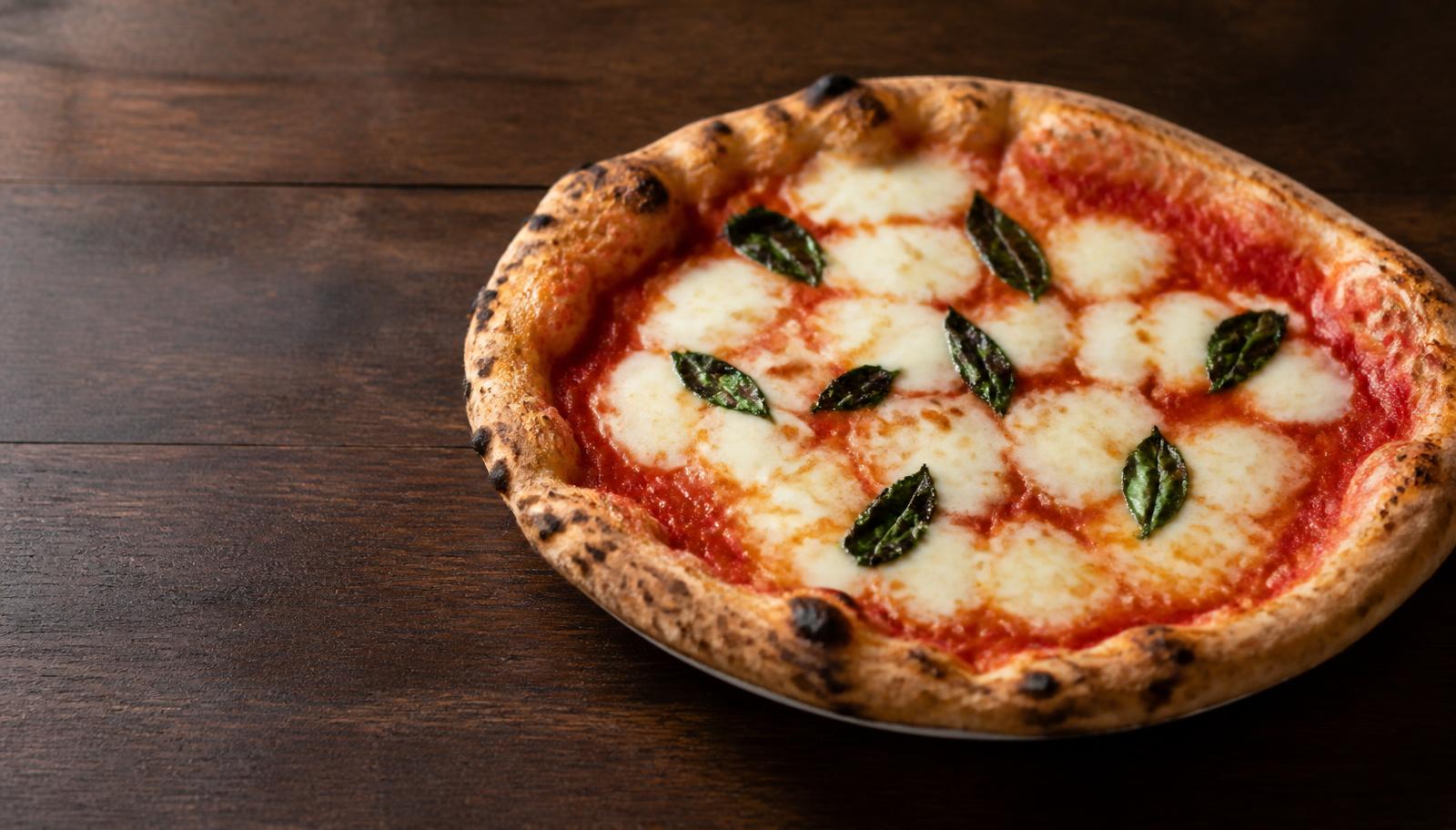 Pizza margherita artigianale appena sfornata su tavolo di legno scuro